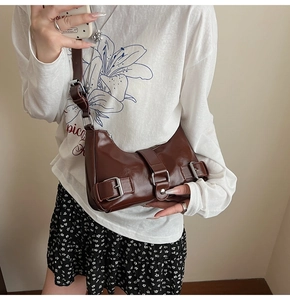 Detailed view of dark brown glossy underarm bag with decorative silver buckles
