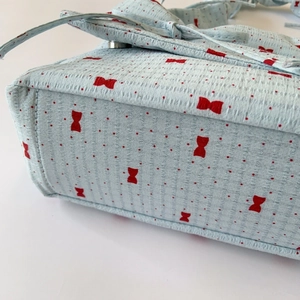 Detail of floral bubble crepe shoulder bag with red bow pattern and textured surface