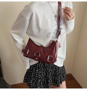 Macro detail of wine red leather bag with glossy finish and silver buckle straps