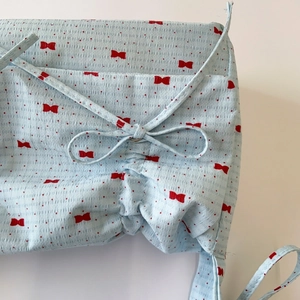 Detailed macro view of light blue seersucker fabric with red bows and gathered drawstring