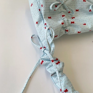 Detailed view of light blue seersucker shoulder strap with red bow and polka dot print