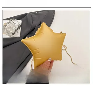 Detail view of a star-shaped yellow PU leather handbag with a gold metal chain strap