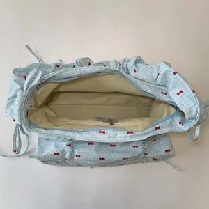 Light blue ruched underarm bag with red bow pattern and ruffled edge design