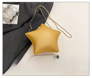 Detailed top view of a yellow star-shaped puffer bag with a gold chain strap on a white surface
