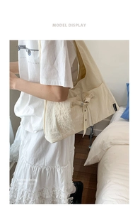 Détail du sac à bandoulière en toile beige avec poche latérale et boucle métallique