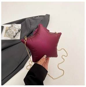 Détail d'un sac bandoulière en forme d'étoile rouge vin avec une chaîne dorée