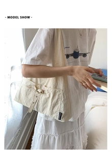 Détail d'un sac cabas beige avec nœud décoratif et poches latérales dans un cadre intérieur