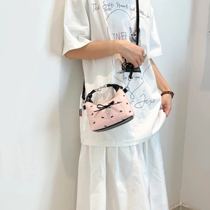 Sac bandoulière jacquard rose avec nœuds noirs et pendentif cœur porté par mannequin