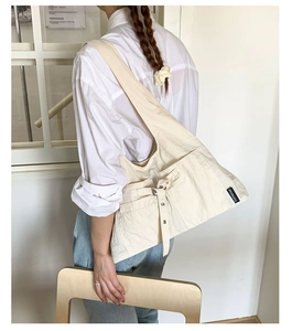 Détail du sac hobo en toile crème avec boucle métallique et étiquette logo tissée