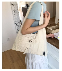 Détail d'un sac fourre-tout en toile beige avec poches décoratives et sangles à boucles