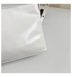Dettaglio ravvicinato della borsa tote in vernice bianca con occhielli in metallo argento