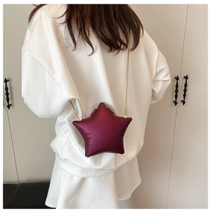 Detail of burgundy star-shaped crossbody bag with metallic chain and embossed texture