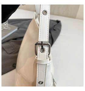 Dettaglio della tracolla regolabile con fibbia argentata su una borsa tote bianca