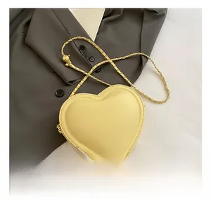 Detail showing heart-shaped crossbody bag with gold chain and ball adjustment buckle