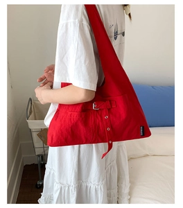 Détail du sac fourre-tout rouge montrant la boucle latérale et l'étiquette de marque
