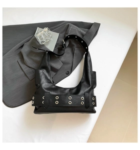 Detail of black faux leather hobo bag with silver metal eyelets and wide belt strap