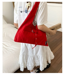 Détail du grand sac fourre-tout en toile rouge avec boucle en métal porté par un mannequin