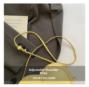 Detail of cream heart-shaped crossbody bag with adjustable gold chain and ball slider