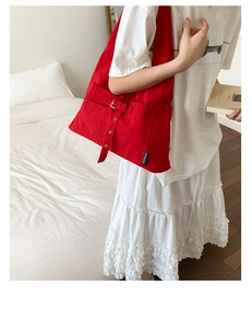 Détail du sac cabas en toile rouge avec boucle décorative et étiquette sur le modèle