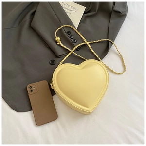 Detailed view of yellow heart-shaped crossbody bag with gold chain strap on blazer