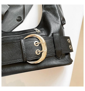 Detail of black faux leather shoulder bag with silver crescent buckles and belt straps