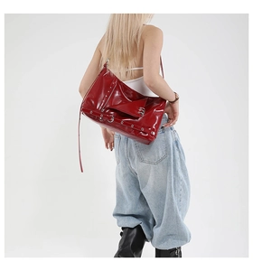 Dettaglio borsa a tracolla in vernice rossa con anelli punk e accessori in metallo