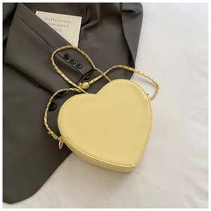 Detail of light yellow heart crossbody bag with gold chain and metal ball clasp