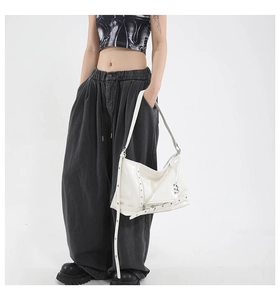 Dettaglio della borsa hobo bianca lucida con borchie e cinturini con fibbia in metallo