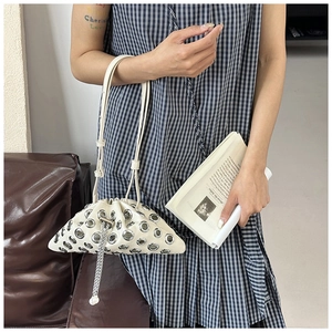 Close-up of white leather eyelet bucket bag featuring silver chain tassel and metal rings