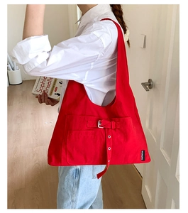 Vue détaillée du grand sac bandoulière en toile rouge montrant la poche et la boucle métal