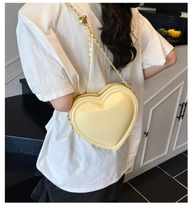 Detail of a heart-shaped yellow crossbody bag with gold chain and adjustable bead