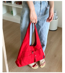Vue détaillée du sac fourre-tout en toile rouge avec poche frontale à boucle et étiquette