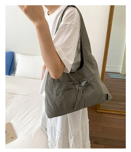 Vue détaillée du sac fourre-tout gris en toile avec poche à boucle et bandoulière