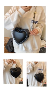 Three-angle views of a black heart-shaped crossbody bag with gold metal chain strap