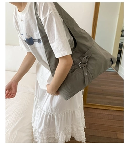 Détail du sac à bandoulière en toile grise avec sangle réglable et boucle en métal