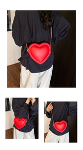 Detail view of red heart-shaped crossbody bag with gold chain strap and smooth faux leather