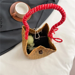 Handmade straw bucket bag with red-white handles and pearl decor, shown from top view