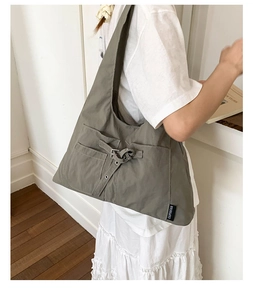 Détail d'un grand sac cabas en toile gris foncé avec boucle décorative et poches latérales