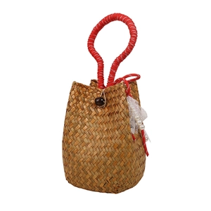Handmade woven straw bucket bag with red handles and pearl lace accents on white background