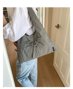 Vue détaillée du sac cabas en toile grise avec poches latérales et boucles en métal