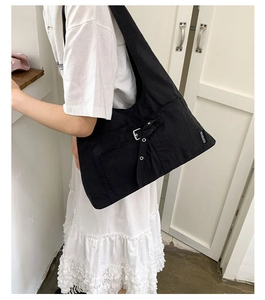 Gros plan du sac bandoulière en toile noire avec boucles argentées et coutures