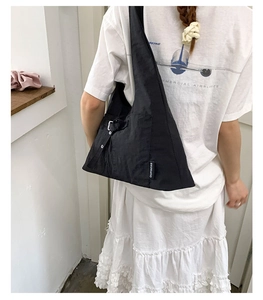 Détails d'un grand sac bandoulière noir en toile avec des boucles réglables sur le côté