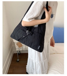 Détail d'un sac cabas en toile noire avec boucle réglable et étiquette tissée