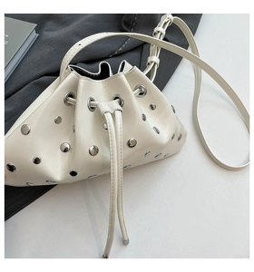 Close-up of cream-white bucket bag with silver metal rivets and drawstring detail