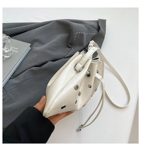 Detail of white patent leather bucket bag with silver studs and drawstring closure