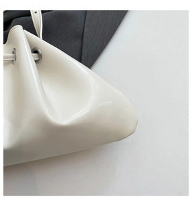 Close-up of white glossy bucket bag showing drawstring detail and silver eyelets