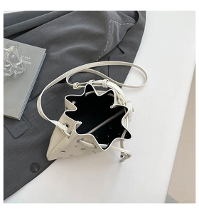 Detailed view of cream grommet crossbody bag with silver eyelets and adjustable strap