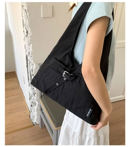 Gros plan sur un sac cabas noir en toile avec poches utilitaires et boucles en métal argenté