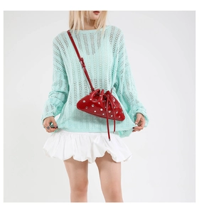 Detail of red glossy rivet cloud bag paired with a mint green knit top and white skirt