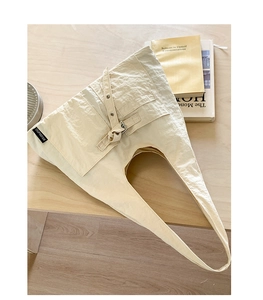 Détail d'un sac hobo en toile crème avec poche style utilitaire et boucle métallique